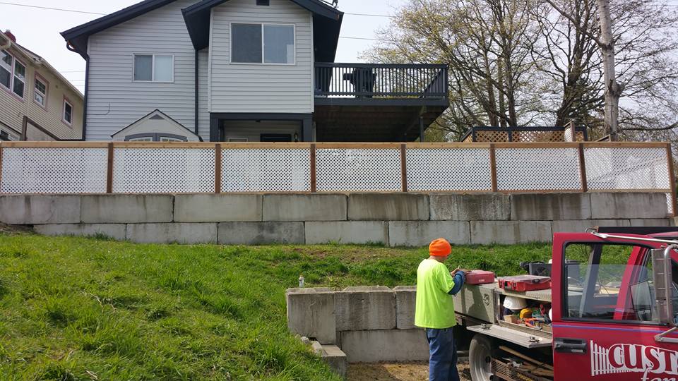 A man in green clothing standing next to a red truck outside a residential home